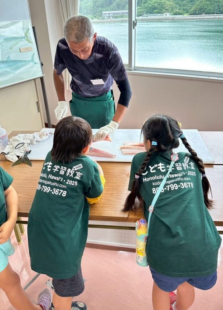 日本留学交流プログラムにて魚を捌く漁師を見る子供たち